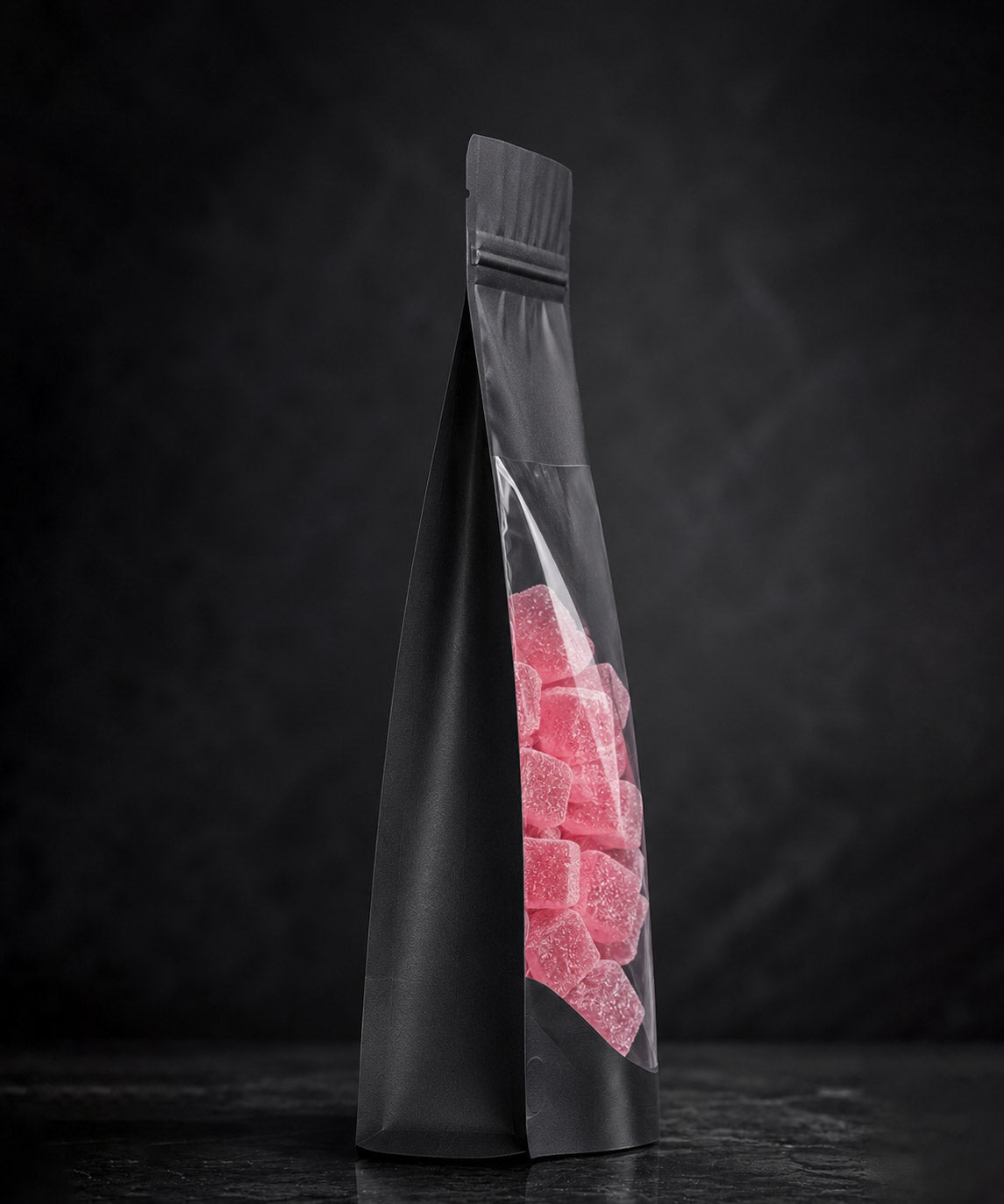 Black plastic bag with pink gummy bears on a dark background